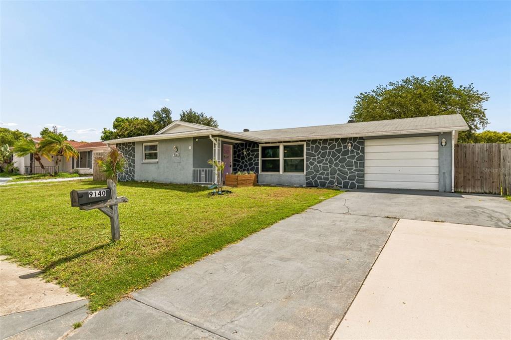 A single-story house with a gray facade, stone accents, and a concrete driveway — 9140 COCHISE LANE, PORT RICHEY, FL