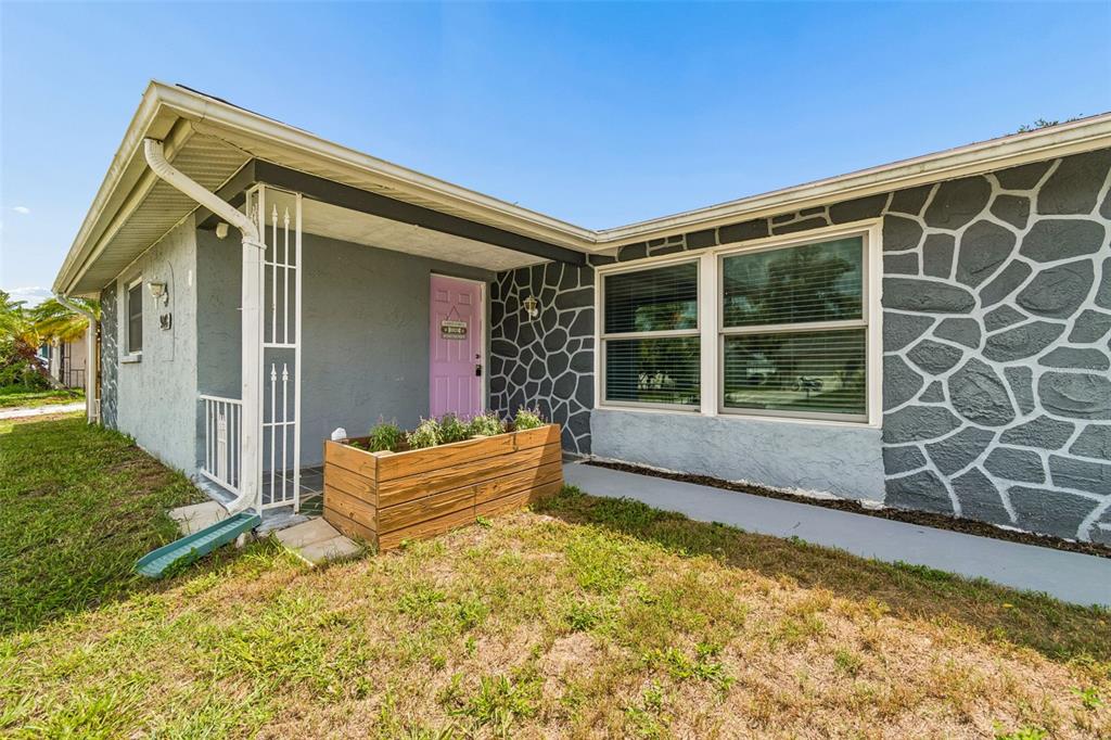 The exterior of a house features a pink front door, stone-patterned siding, and a planter — 9140 COCHISE LANE, PORT RICHEY, FL