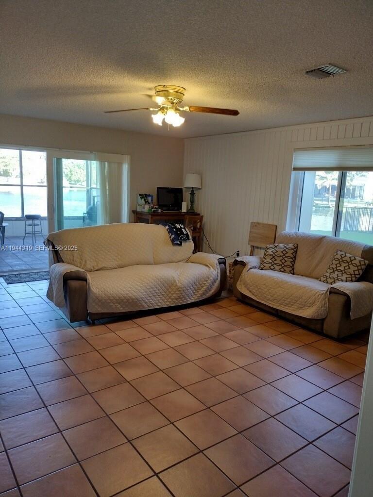 A living room features tile flooring, two sofas with covers, and a ceiling fan — 14531 Hickory Ct, Davie FL 33325, DAVIE, FL