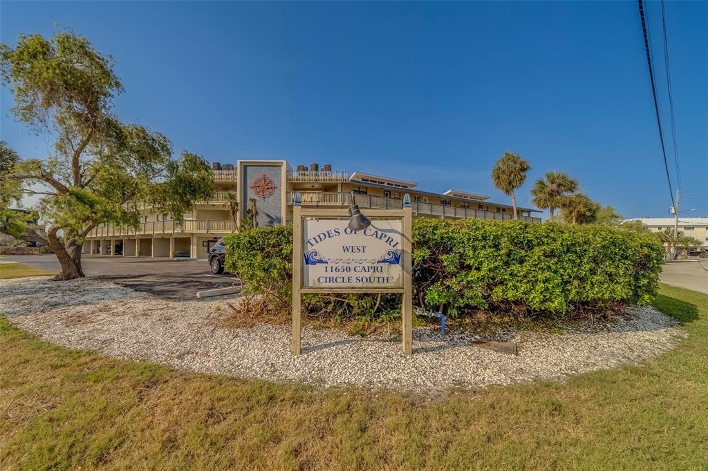 A sign for Tides of Capri West stands in front of a multi-story apartment building — 11650 CAPRI CIRCLE S UNIT 105, TREASURE ISLAND, FL
