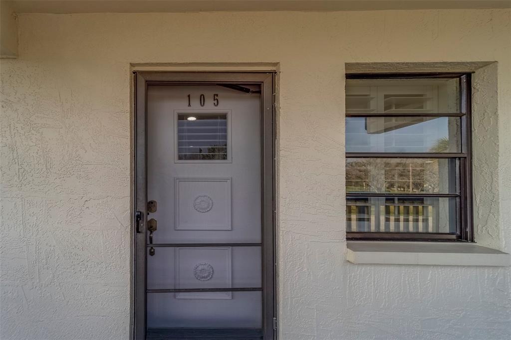 A light-colored exterior wall features a front door numbered 105 and an adjacent window — 11650 CAPRI CIRCLE S UNIT 105, TREASURE ISLAND, FL