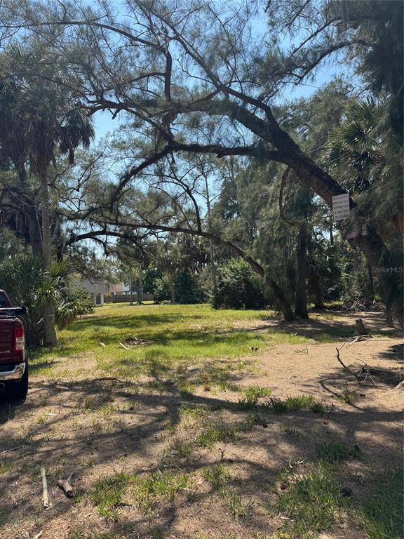 A vacant, grassy lot features several large trees and a partial view of a vehicle — 7103 OAKWOOD DRIVE, NEW PORT RICHEY, FL