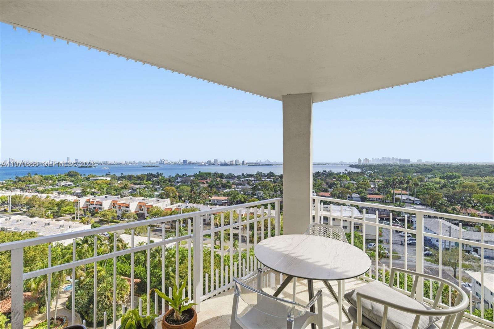 A high-rise balcony features a small round table, chairs, and a panoramic waterfront city view — 2000 Towerside Ter # 1408, Miami FL 33138, MIAMI, FL