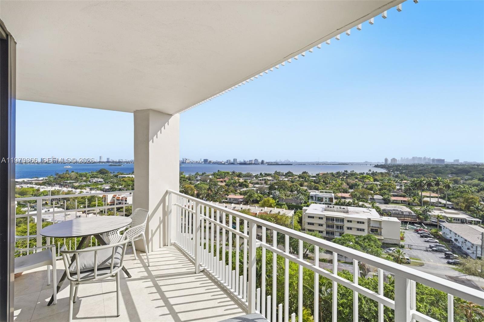 A balcony with a table and chairs overlooks a bay and city skyline — 2000 Towerside Ter # 1408, Miami FL 33138, MIAMI, FL