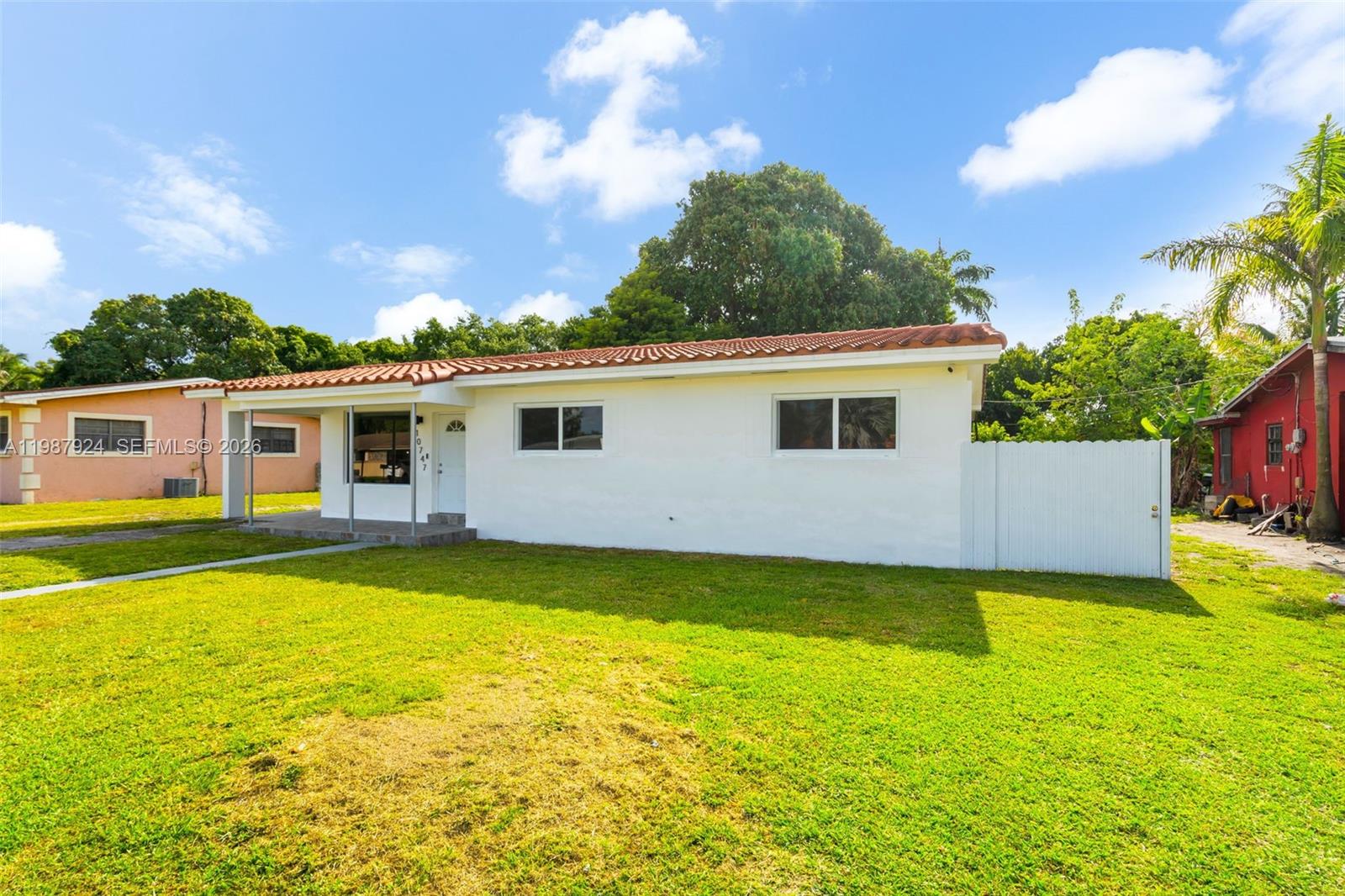 A white single-story house with a red tile roof sits on a grassy lawn — 10747 NW 22nd Ct, Miami FL 33167, MIAMI, FL