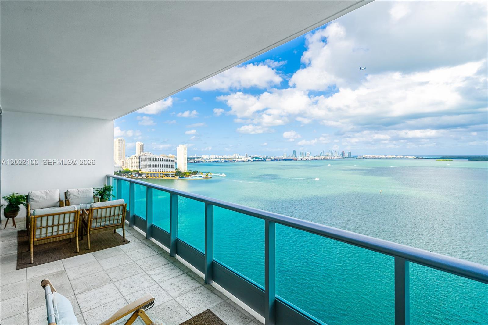 A balcony with outdoor furniture overlooks a large body of water and a city skyline — 1331 Brickell Bay Dr # 2007, Miami FL 33131, MIAMI, FL