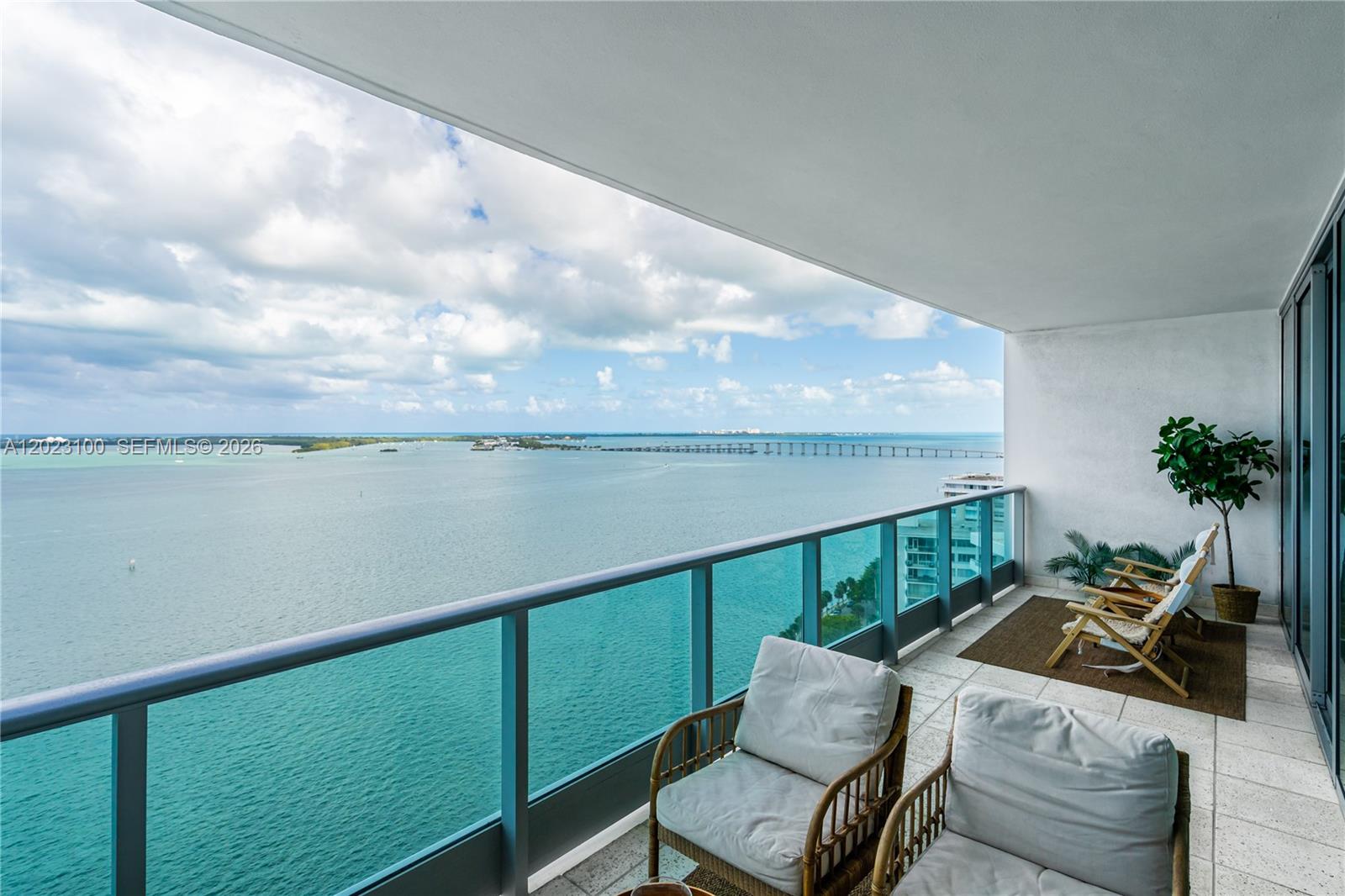 A high-rise balcony features outdoor seating overlooking a large body of water and bridge — 1331 Brickell Bay Dr # 2007, Miami FL 33131, MIAMI, FL
