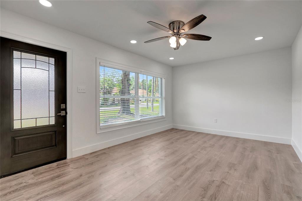 A room with light wood-look flooring, white walls, a ceiling fan, and a front door — 6703 N BOULEVARD, TAMPA, FL