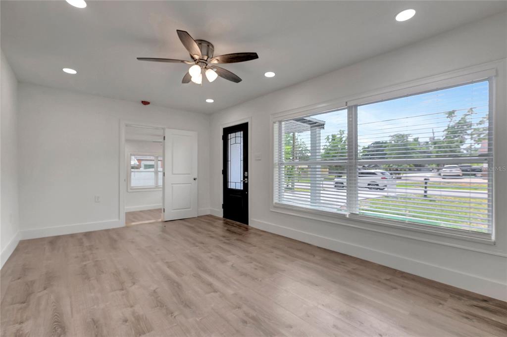 A bright room features light wood-look flooring, a ceiling fan, and a black exterior door — 6703 N BOULEVARD, TAMPA, FL