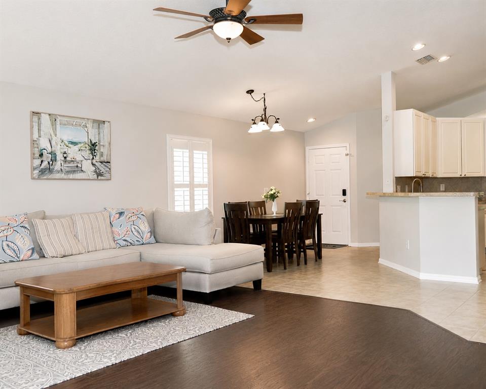 A living room with a sectional sofa, coffee table, and adjacent dining area with tile flooring — 10839 NEWBRIDGE DRIVE, RIVERVIEW, FL