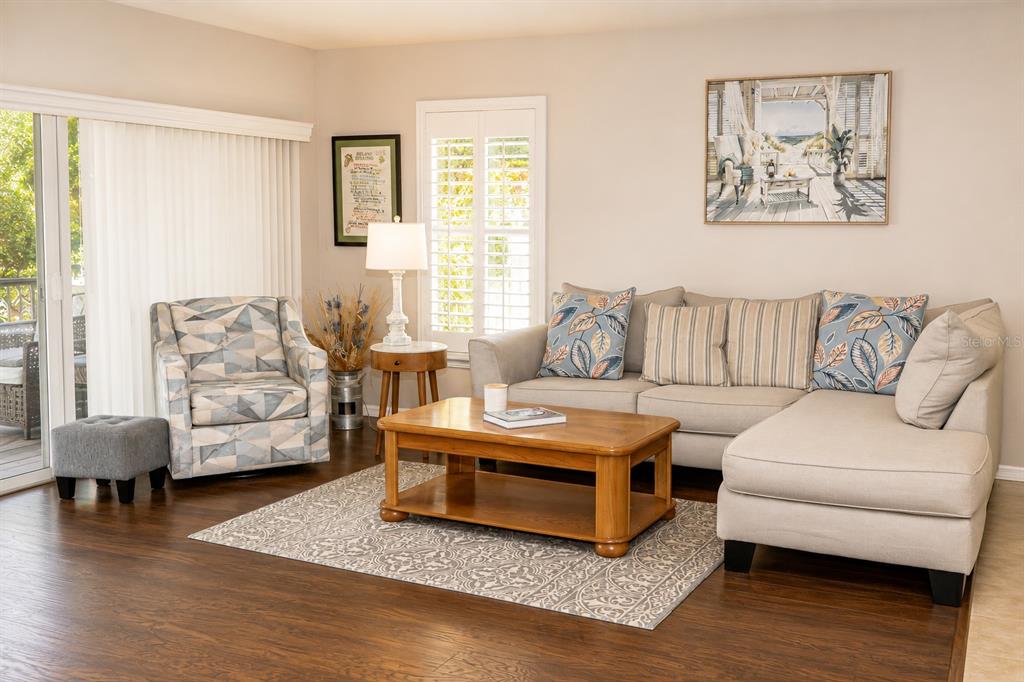 A living room features a sectional sofa, patterned armchair, wooden coffee table, and hardwood floors — 10839 NEWBRIDGE DRIVE, RIVERVIEW, FL