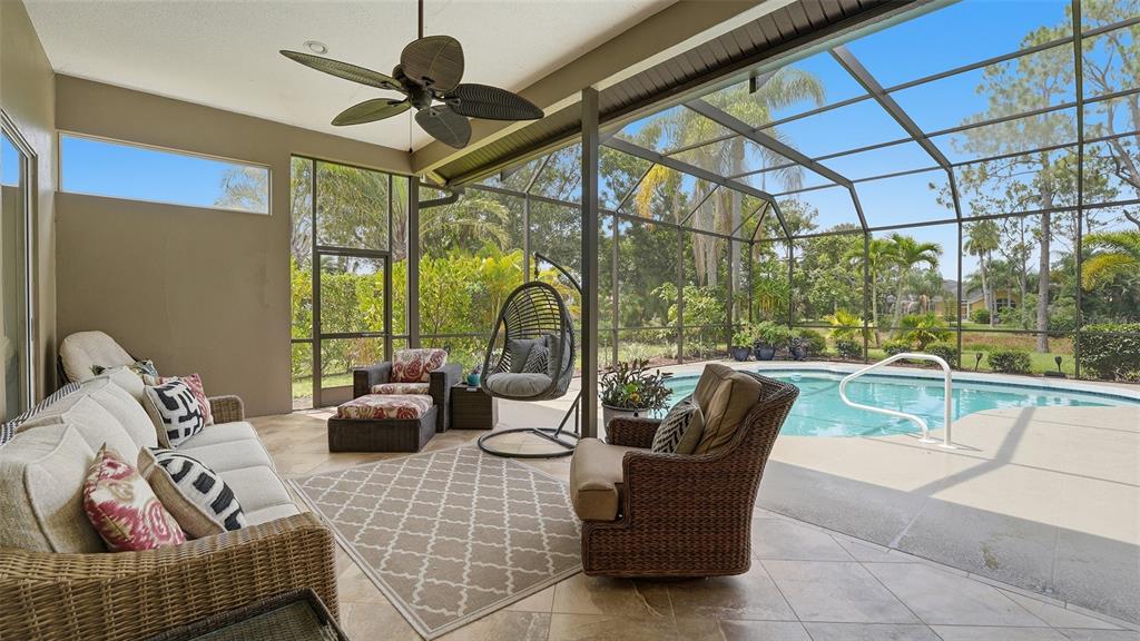 A screened-in patio features a seating area, a ceiling fan, and a swimming pool — 7117 DORNOUGH LANE, BRADENTON, FL