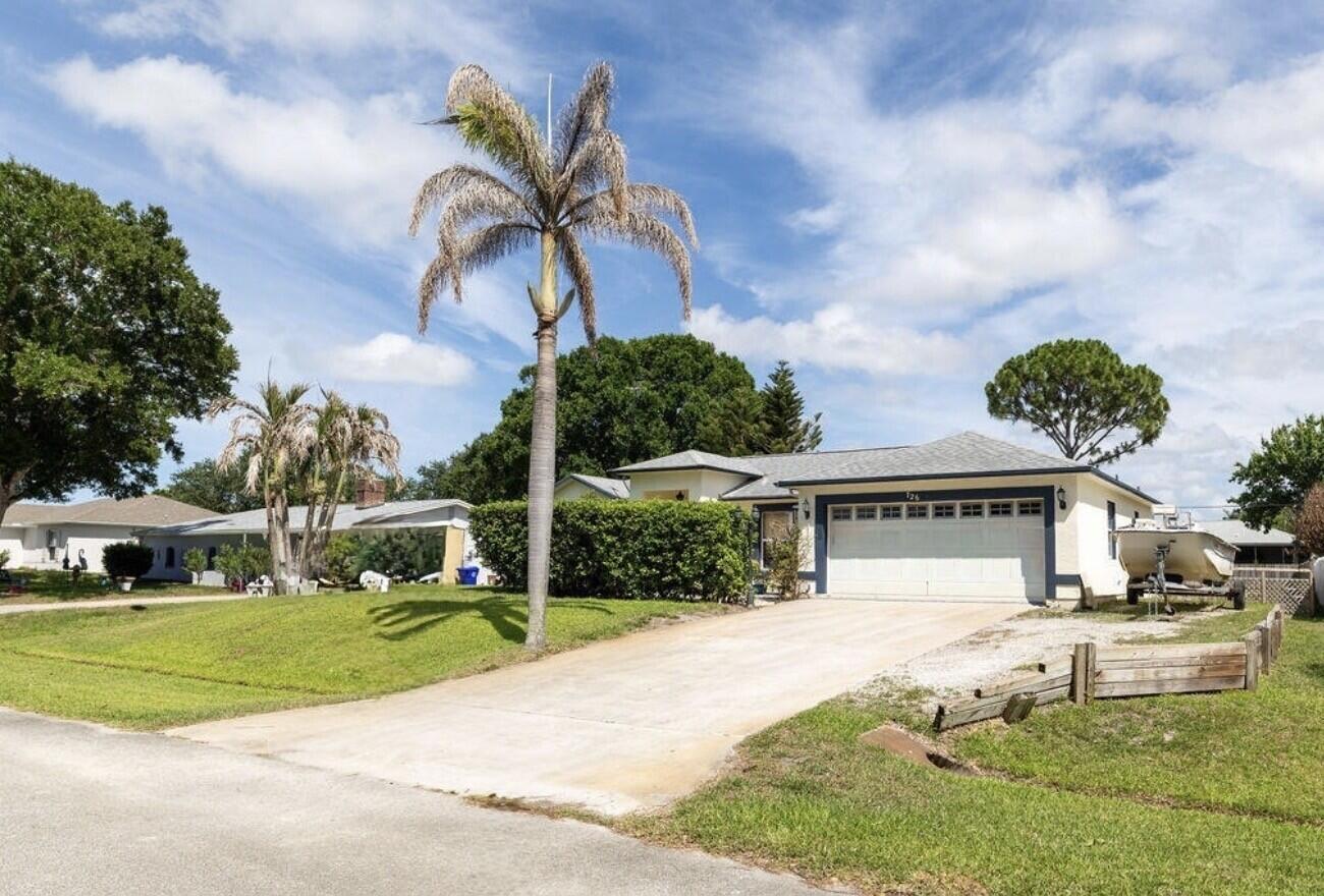 A single-story house with a white garage, a concrete driveway, and a tall palm tree — 726 Tuxedo Terrace, Sebastian FL 32958, SEBASTIAN, FL