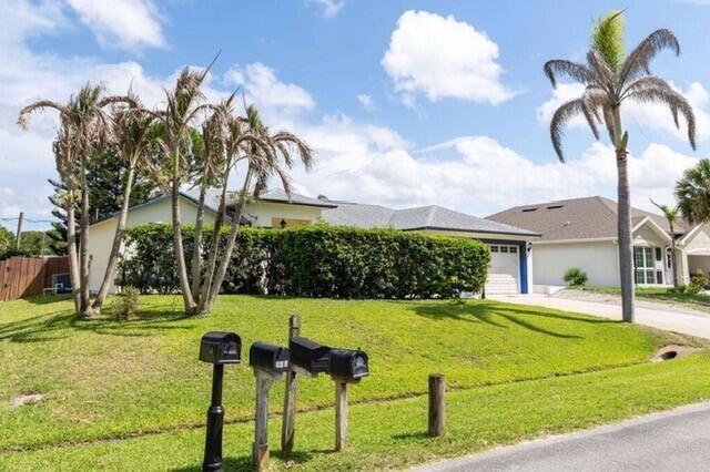 A single-story house with a large hedge and palm trees sits behind several mailboxes — 726 Tuxedo Terrace, Sebastian FL 32958, SEBASTIAN, FL