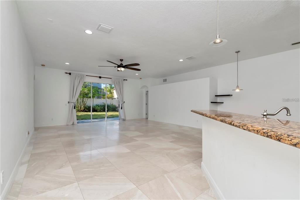 An open-concept living area features light tile flooring, a ceiling fan, and sliding glass doors — 29822 BOYETTE OAKS PLACE, WESLEY CHAPEL, FL