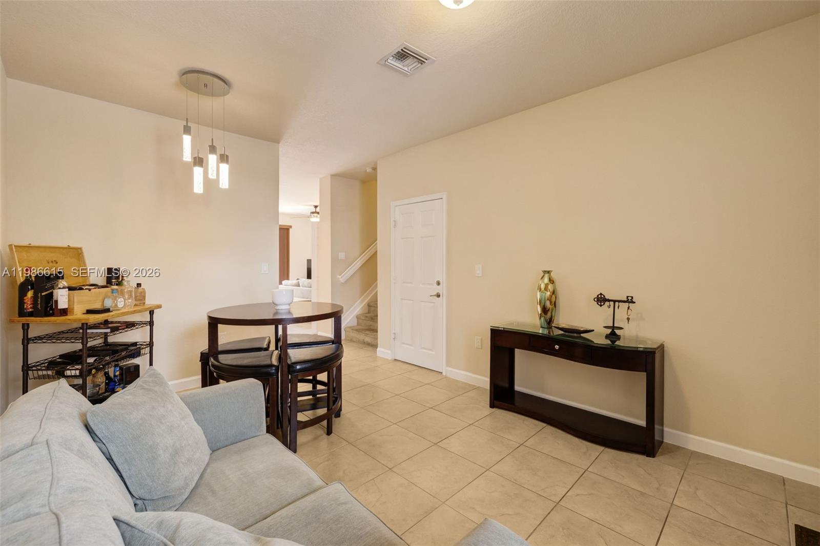 A living area features tile flooring, a dining table, a console table, and a staircase — 4233 SW 164th Ct, Miami FL 33185, MIAMI, FL