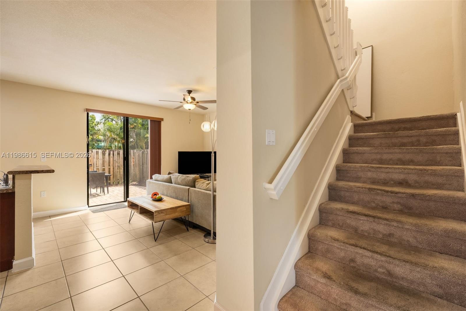 A carpeted staircase leads upstairs next to a tiled living area with a sliding door — 4233 SW 164th Ct, Miami FL 33185, MIAMI, FL