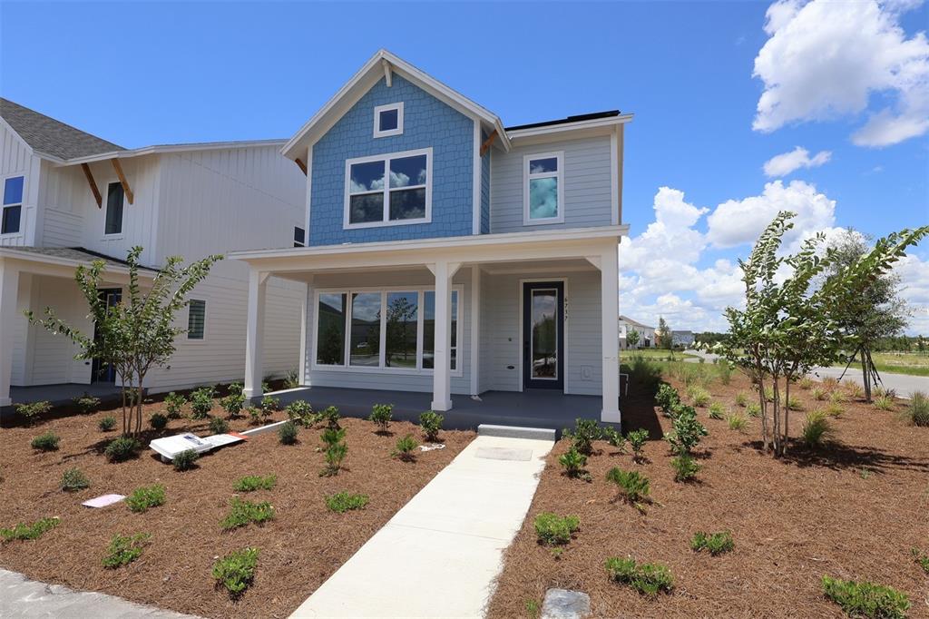 A two-story house with blue shingle siding and a front porch faces a paved road — 6737 FOUNTAIN GROVE PASS, ST CLOUD, FL