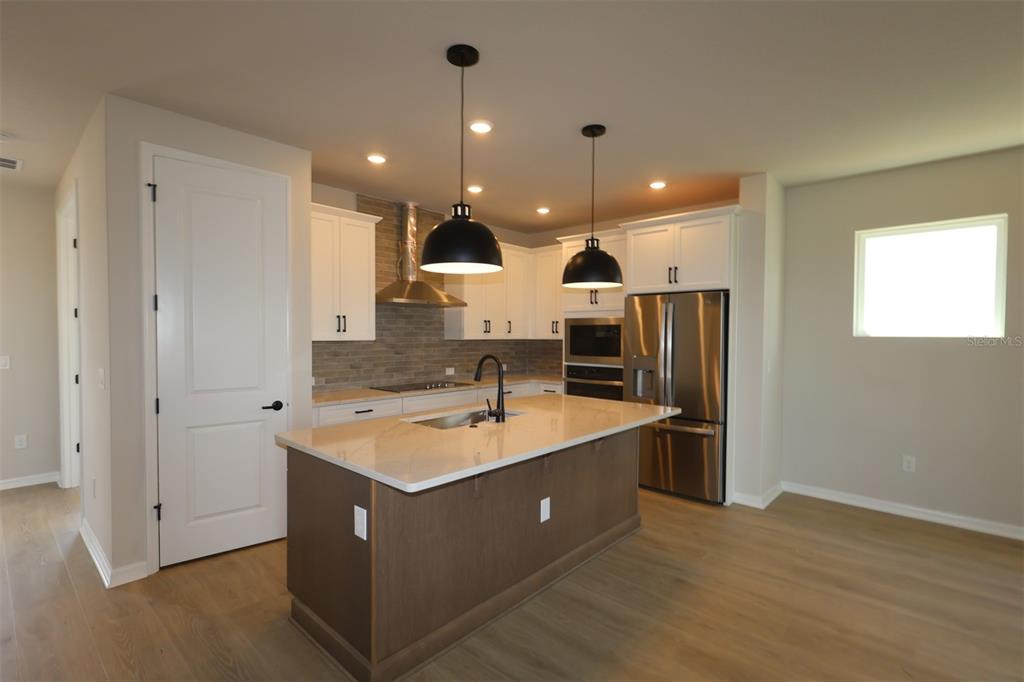 An empty room with light wood-look flooring, white walls, and French doors leading to another room — 6737 FOUNTAIN GROVE PASS, ST CLOUD, FL