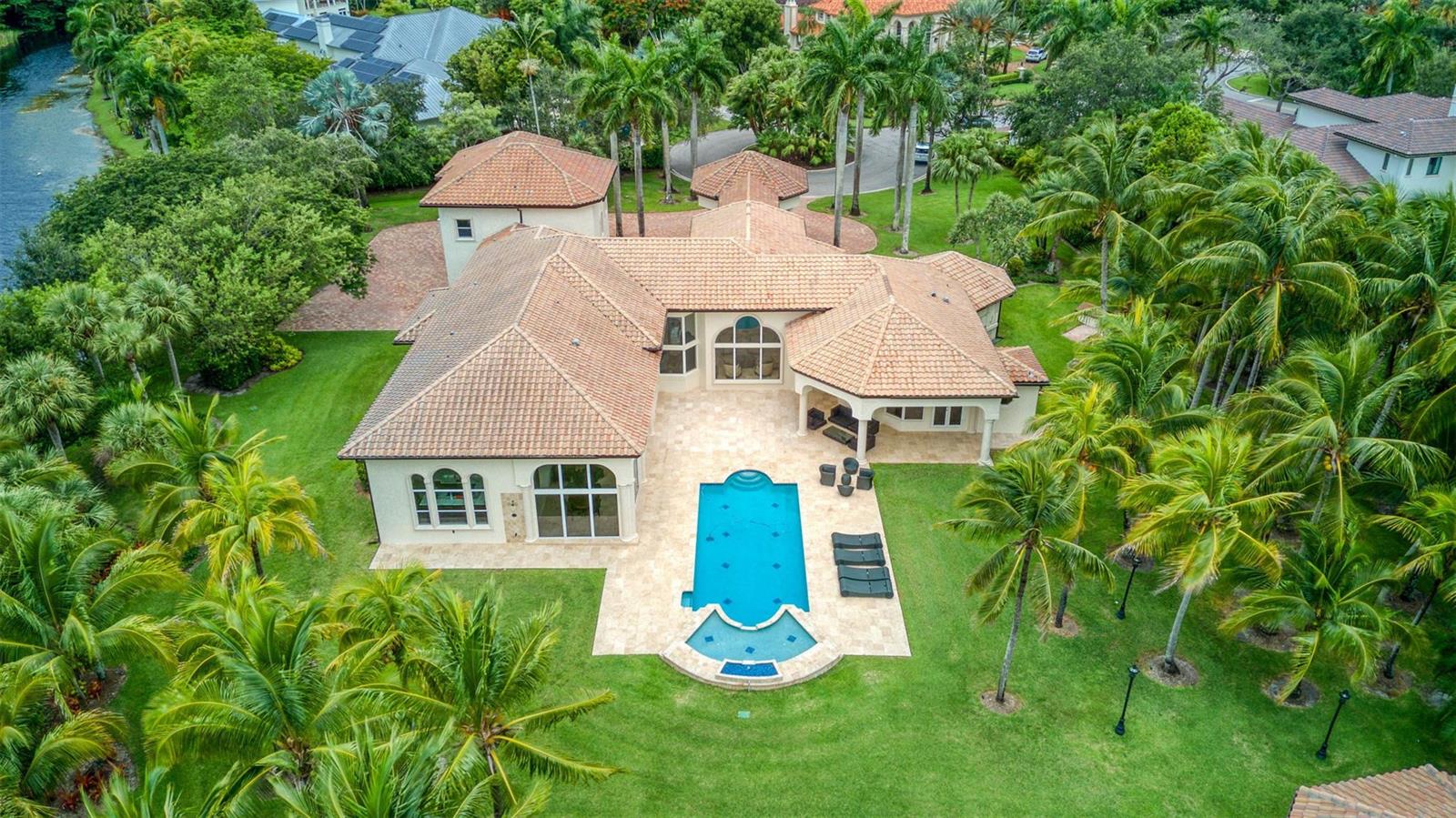 An aerial view of a house with a tiled roof, swimming pool, and surrounding palm trees — 3440 Stallion Lane, Weston FL 33331, WESTON, FL