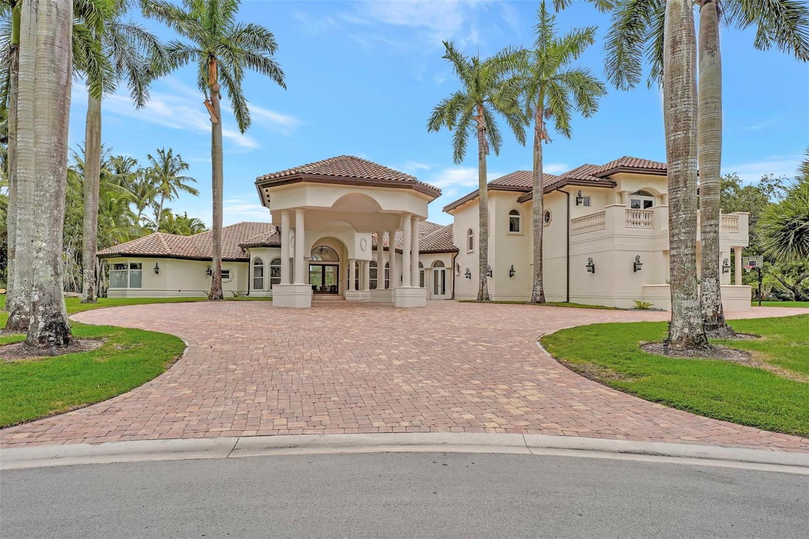 A large, two-story Mediterranean-style house with a paved driveway and tall palm trees — 3440 Stallion Lane, Weston FL 33331, WESTON, FL