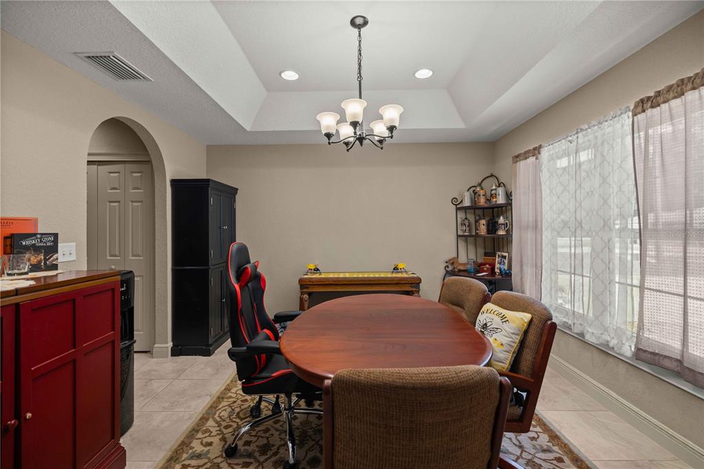A dining room features a wooden table, chairs, a tray ceiling, and tile flooring — 162 GUAVA TERRACE, OCKLAWAHA, FL
