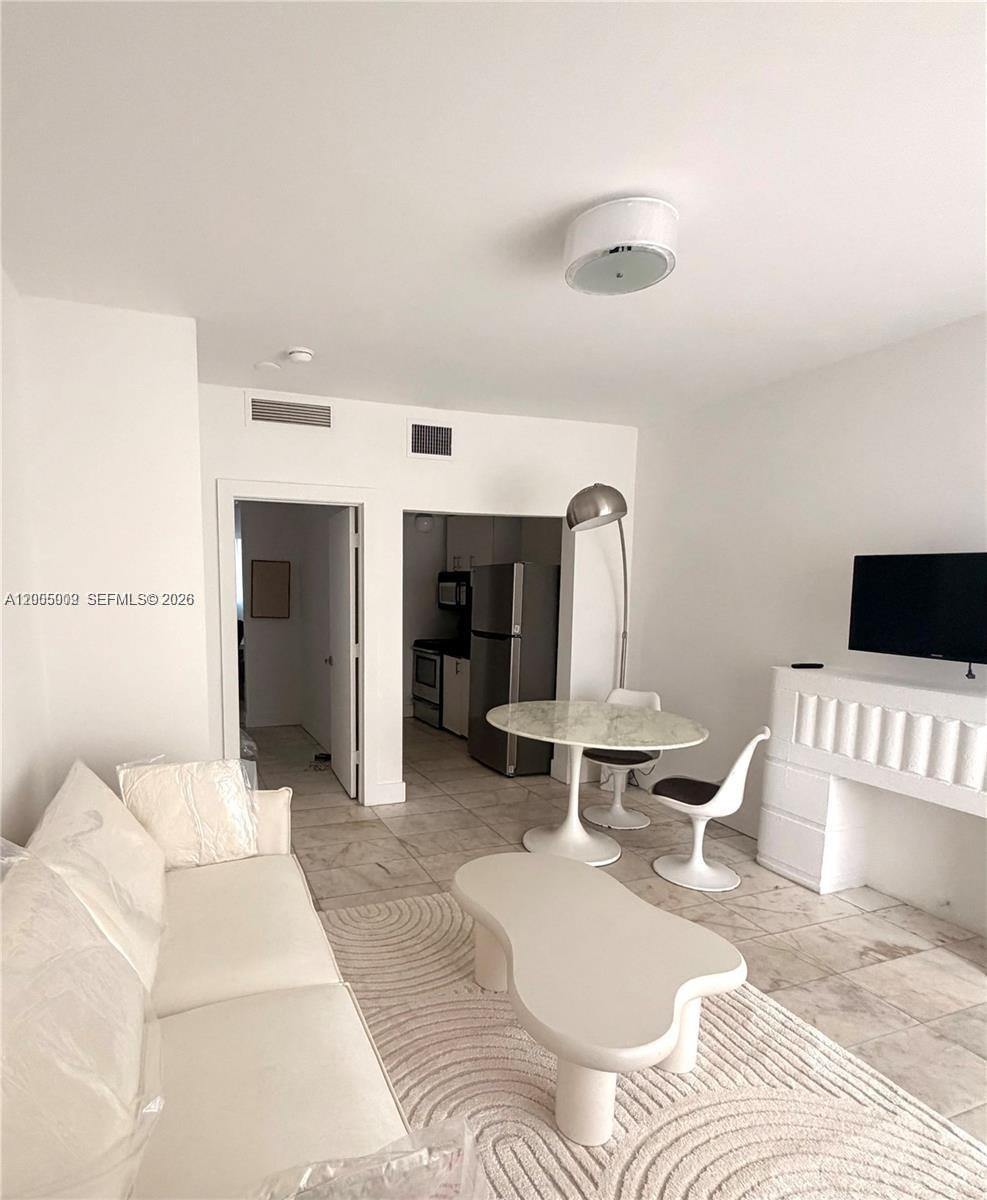 A living room features a white sofa, a coffee table, and a dining area — 801 8th St # 104, Miami Beach FL 33139, MIAMI BEACH, FL