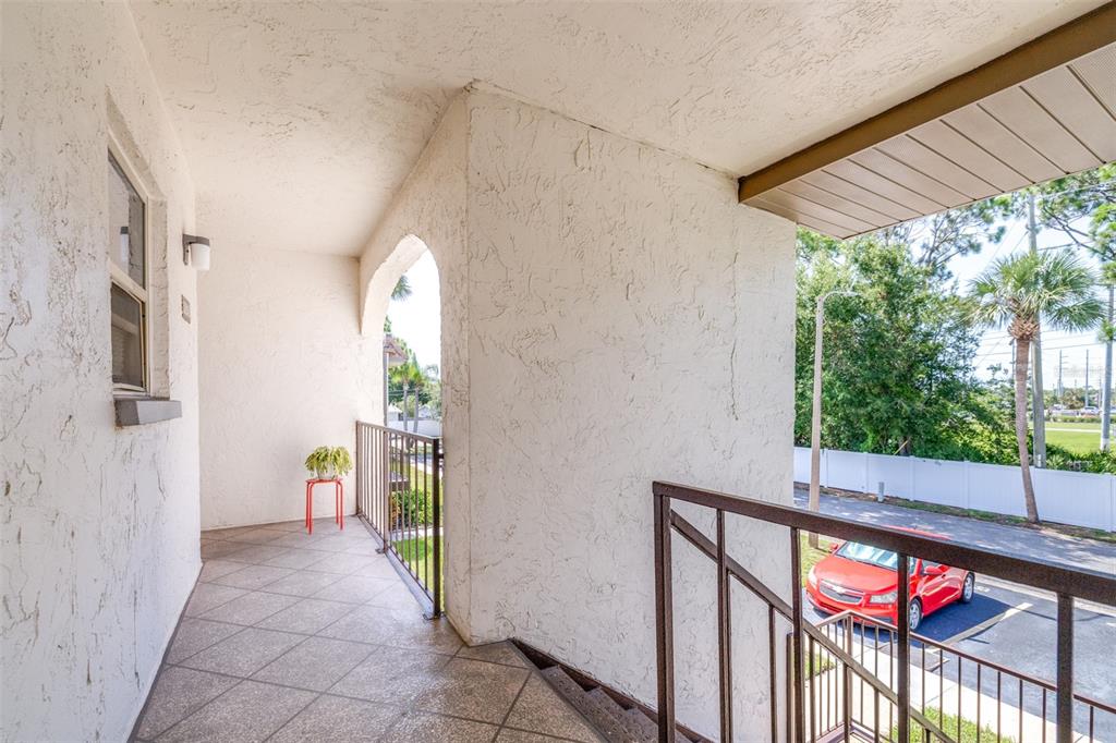 A covered outdoor balcony with a tiled floor, metal railings, and a view of parking — 7701 STARKEY ROAD UNIT 528, SEMINOLE, FL