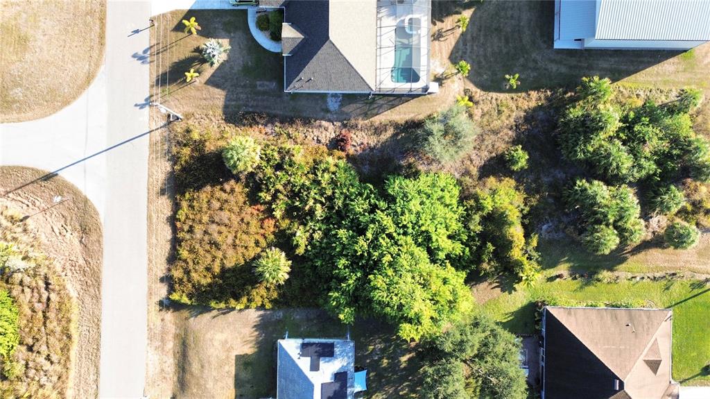 An aerial view shows a vacant, wooded residential lot situated between two houses — LOT 25, LEOPOLD AVENUE, NORTH PORT, FL