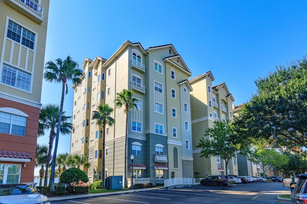 A multi-story apartment building with balconies and palm trees stands beside a parking lot — 8761 THE ESPLANADE UNIT 31, ORLANDO, FL
