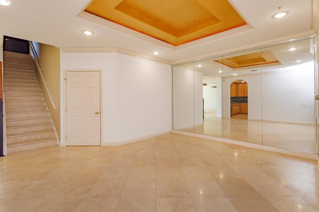 A room with beige tile flooring, a staircase, a white door, and a mirrored wall — 8761 THE ESPLANADE UNIT 31, ORLANDO, FL