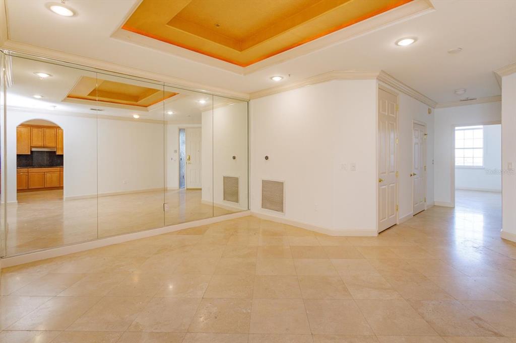 An interior room features large wall mirrors, beige tile flooring, and a recessed tray ceiling — 8761 THE ESPLANADE UNIT 31, ORLANDO, FL