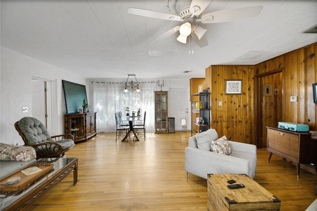 A living and dining area features hardwood floors, wood-paneled walls, and a ceiling fan — 114 PARK AVENUE, FRUITLAND PARK, FL