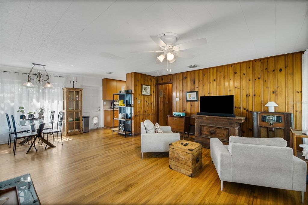 A living and dining area features wood-paneled walls, hardwood floors, and a ceiling fan — 114 PARK AVENUE, FRUITLAND PARK, FL