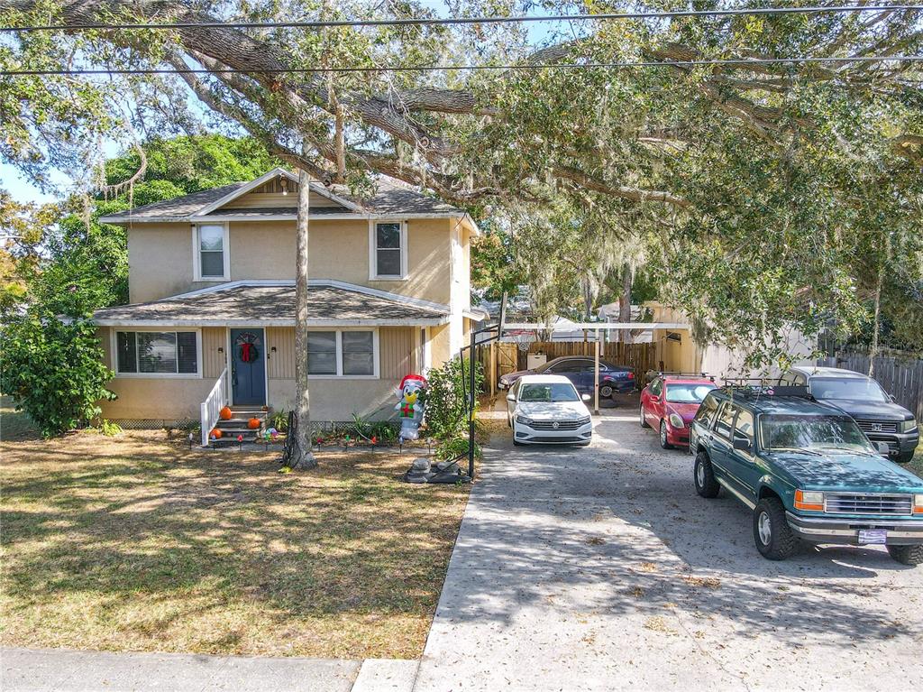 A two-story house with a driveway, multiple parked cars, and large oak trees — 1765 KINGS HIGHWAY, CLEARWATER, FL