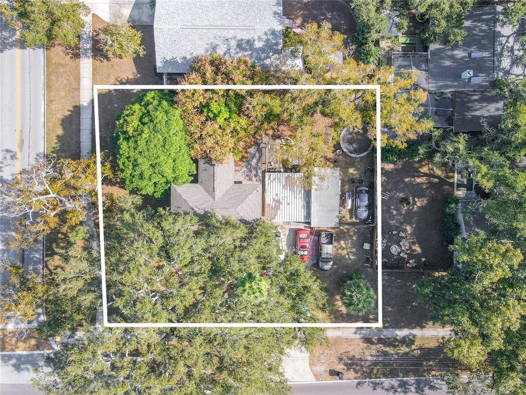 An aerial view shows a house with a metal roof and trees on a lot — 1765 KINGS HIGHWAY, CLEARWATER, FL
