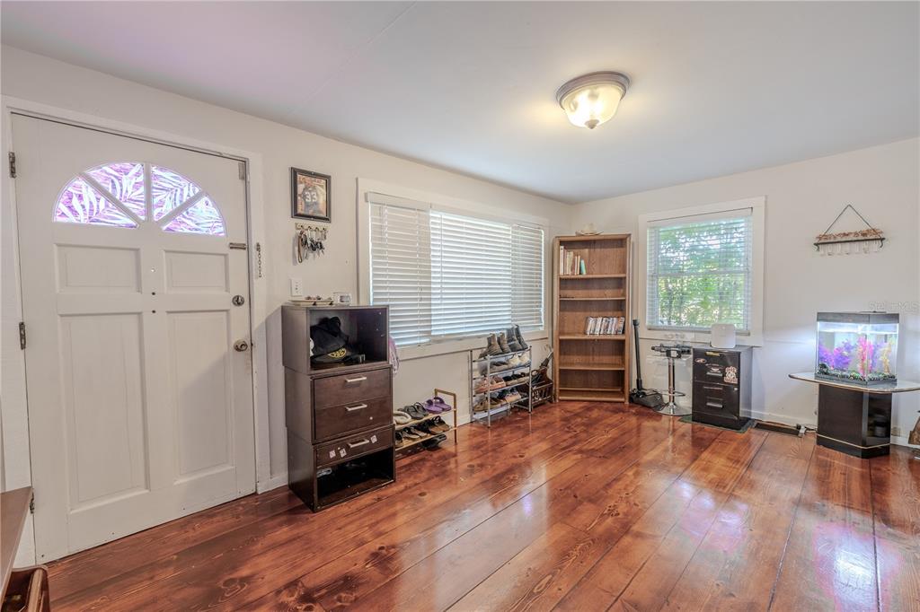 A room with hardwood floors, a white front door, a bookshelf, and a fish tank — 1765 KINGS HIGHWAY, CLEARWATER, FL