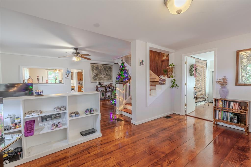 A living room with hardwood floors, a white shelving unit, and a staircase with lights — 1765 KINGS HIGHWAY, CLEARWATER, FL