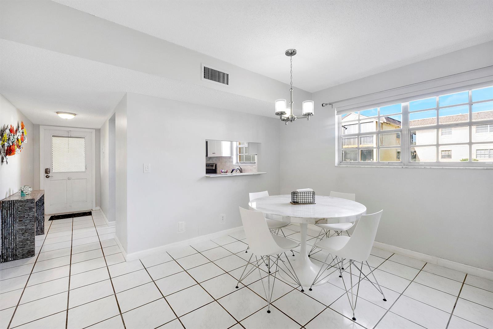 A dining area features white tile floors, a round marble table, and a pass-through window — 1700 Dover Road # a, Delray Beach FL 33445, DELRAY BEACH, FL