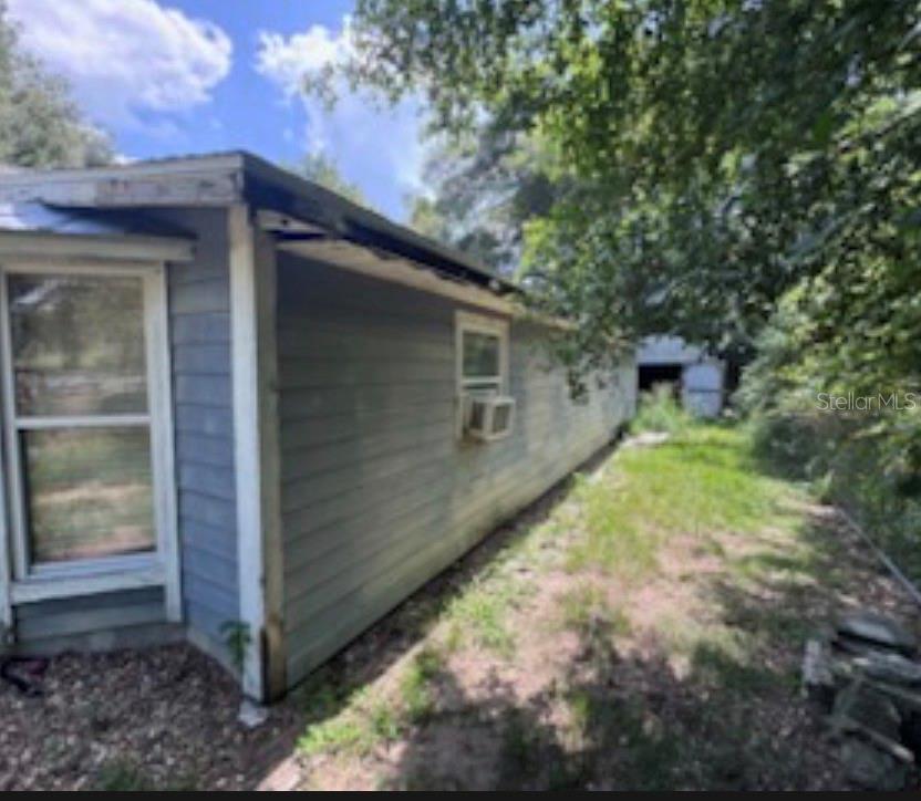 The exterior side of a blue-sided house features a window with an installed air conditioner — 38124 ILLINOIS STREET, LADY LAKE, FL