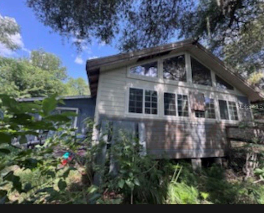 A two-story house exterior features light-colored siding, large windows, and a wooden deck — 38124 ILLINOIS STREET, LADY LAKE, FL