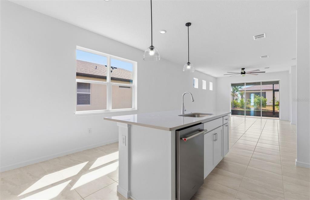 A kitchen island with a stainless steel dishwasher sits in a bright, tiled open-concept room — 5958 SW 86TH AVENUE ROAD, OCALA, FL