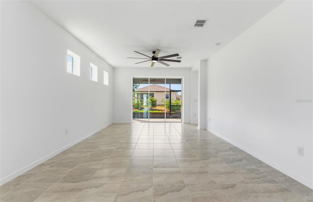 An empty room with white walls, tile flooring, a ceiling fan, and sliding glass doors — 5958 SW 86TH AVENUE ROAD, OCALA, FL