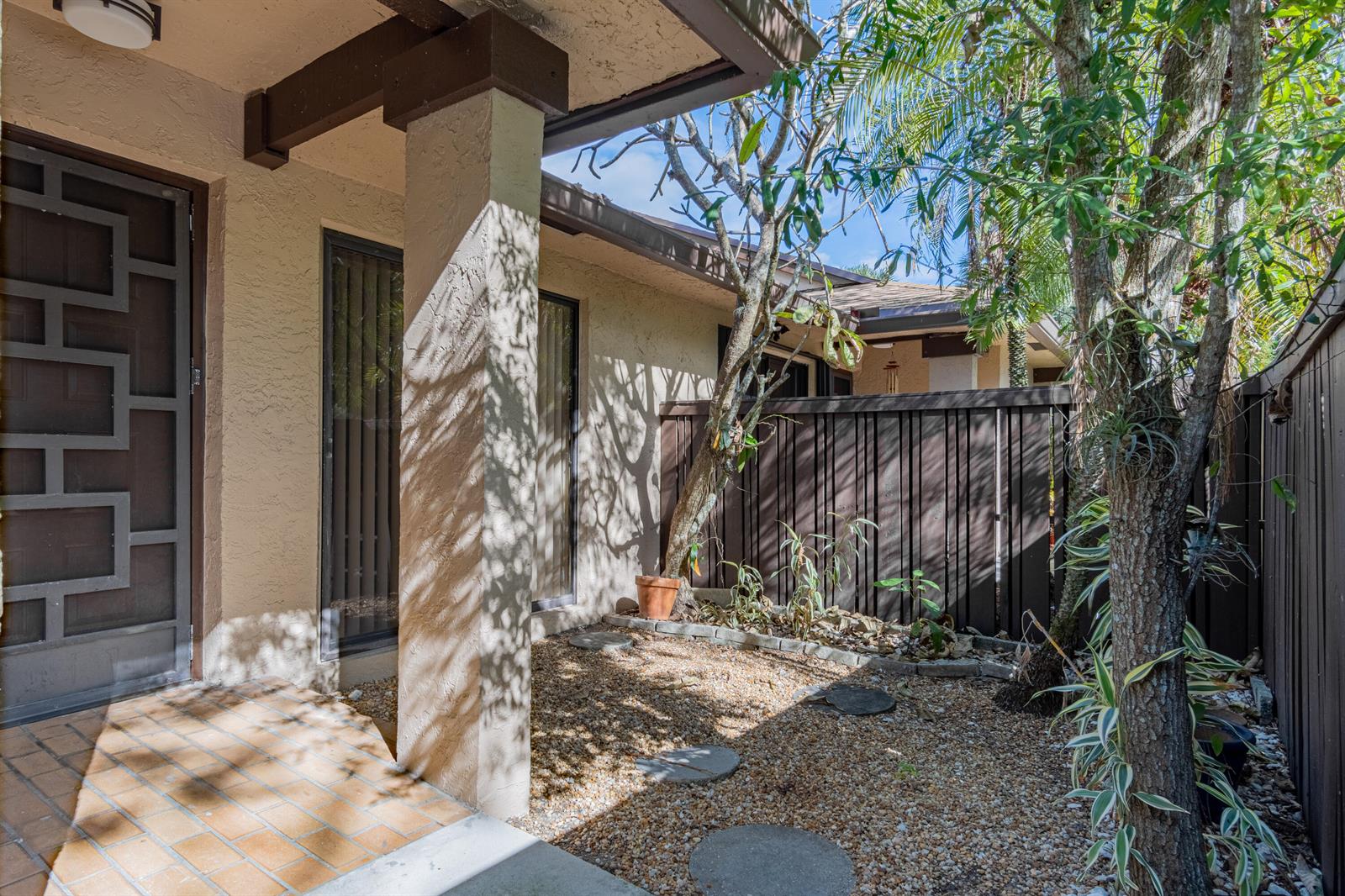 A covered entryway features a patterned door, a stone pillar, and a gravel courtyard area — 8689 W Boca Glades Boulevard W # B, Boca Raton FL 33434, BOCA RATON, FL