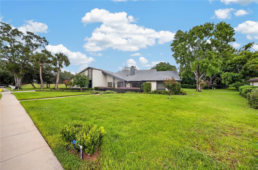 A single-story house with a gray roof and tan siding sits on a large lawn — 190 CANTERCLUB TRAIL NW, LONGWOOD, FL