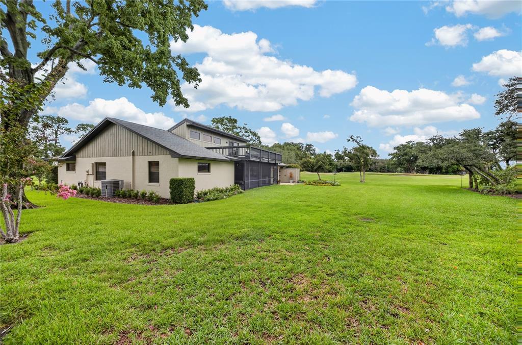 The exterior of a two-story house with a screened porch sits on a large lawn — 190 CANTERCLUB TRAIL NW, LONGWOOD, FL