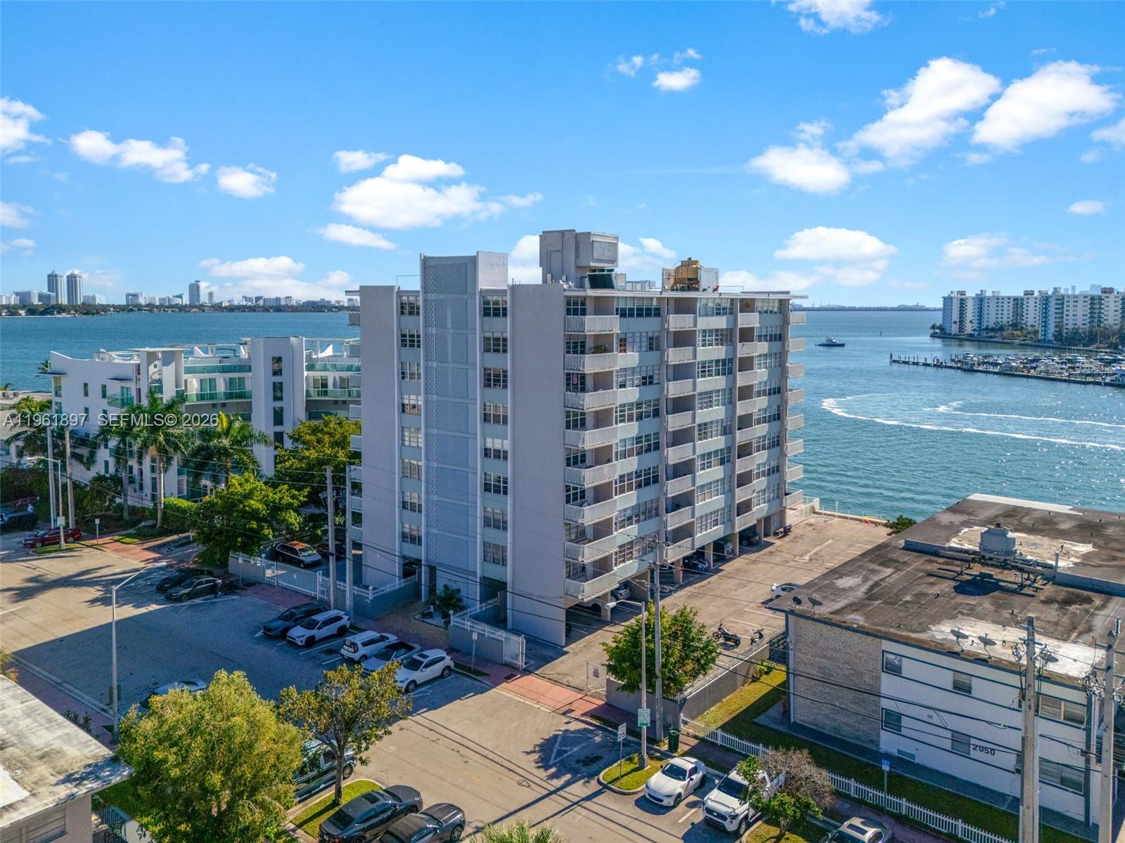 An aerial view shows a multi-story apartment building situated along a waterfront with parking — 2016 Bay Dr # 203, Miami Beach FL 33141, MIAMI BEACH, FL