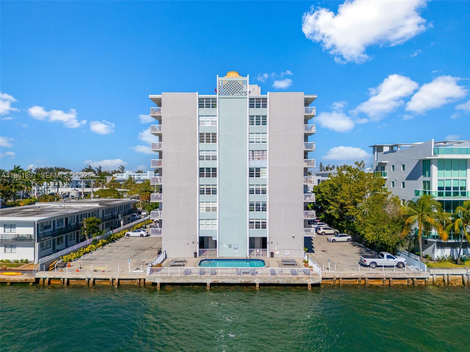 An aerial view shows a multi-story apartment building with a waterfront pool and parking lot — 2016 Bay Dr # 203, Miami Beach FL 33141, MIAMI BEACH, FL