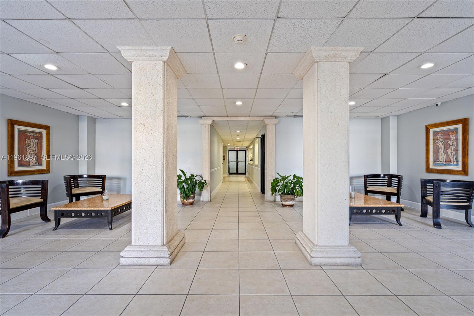 A symmetrical lobby features two large stone columns, tiled flooring, and matching seating areas — 2016 Bay Dr # 203, Miami Beach FL 33141, MIAMI BEACH, FL