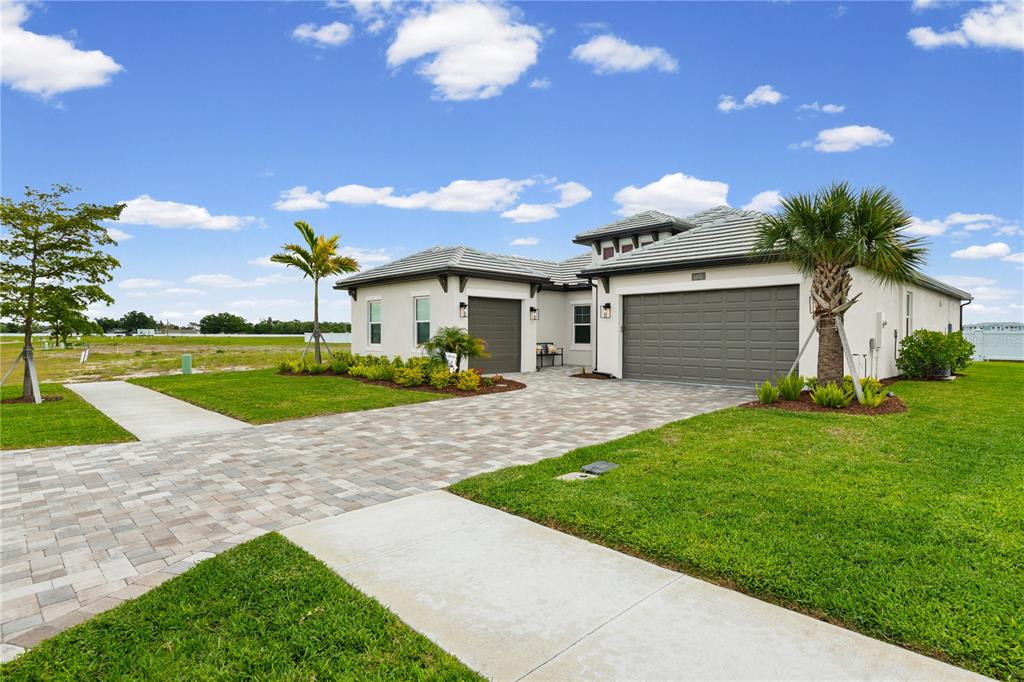A single-story house with a paved driveway, two garage doors, and a landscaped front yard — 1652 LUGANO CIRCLE, NOKOMIS, FL
